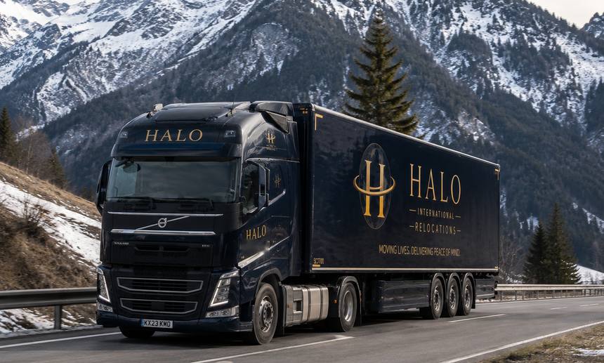 A Halo articulated lorry on an alpine pass, crossing Europe under snow-covered mountains